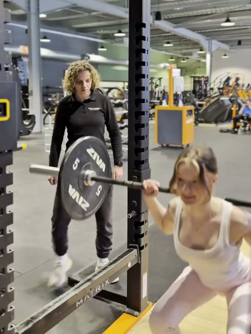 Maelys encadre une cliente pendant une séance de squat en salle de sport